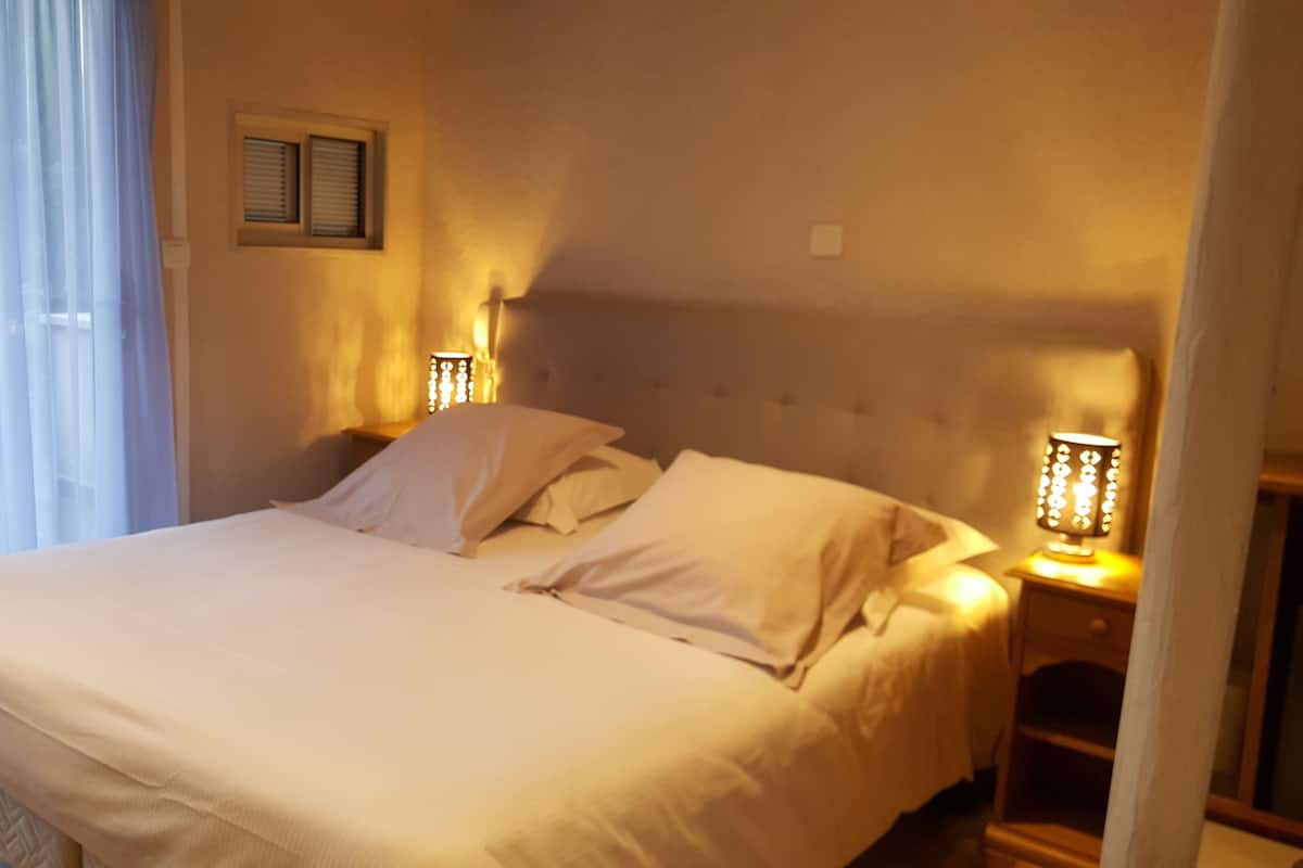 A neatly made bed with white linens in a room with a tufted headboard. There are two bedside lamps on either side of the bed.