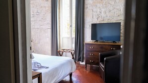 Una habitación de hotel con una cama, un aparador de madera con un televisor y una ventana con cortinas.