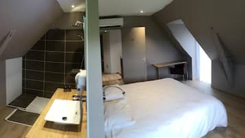 A modern bedroom with a large bed, a shower, and a desk area.