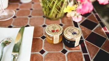 Two jars of preserves on a tiled table with a knife and spoon.