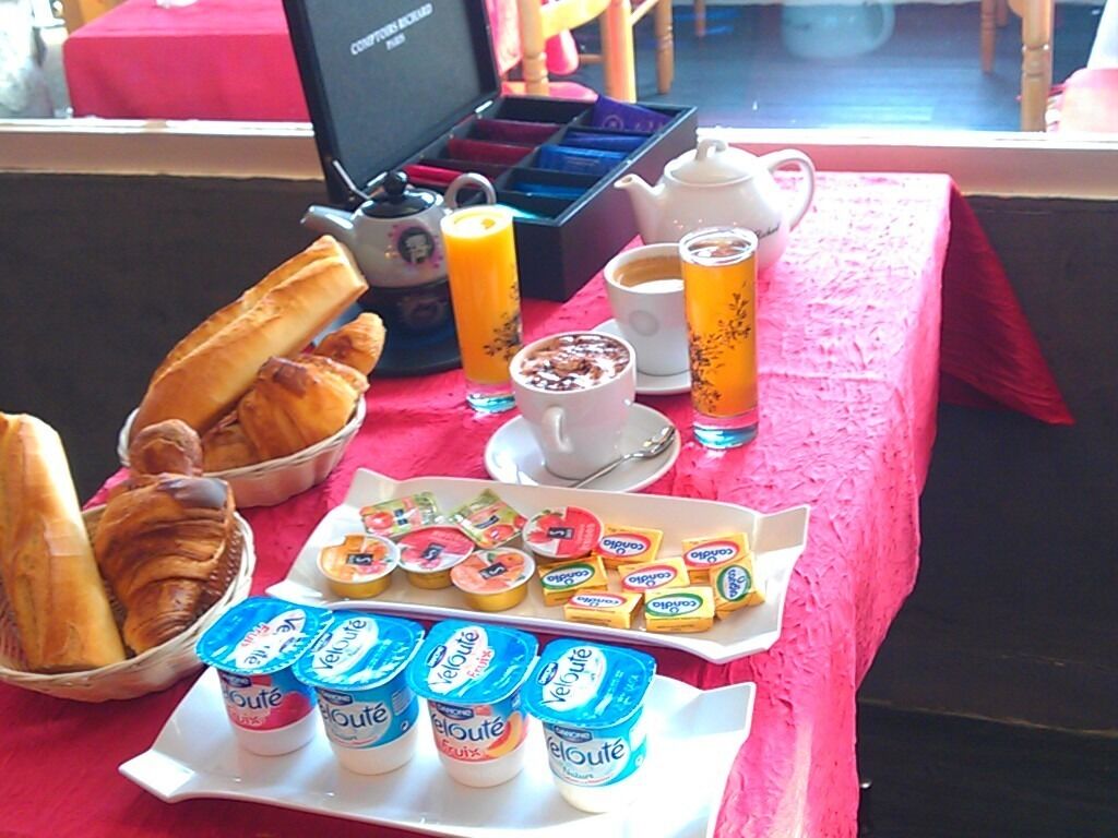 Et morgenbord med croissanter, yoghurt, juice og et thekande.