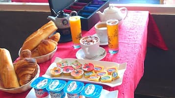 Et morgenbord med croissanter, yoghurt, juice og et thekande.