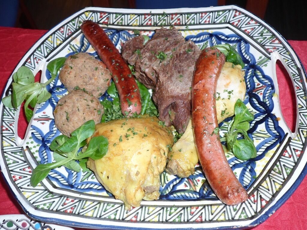 Un plato de comida con salchichas, carne y verduras.