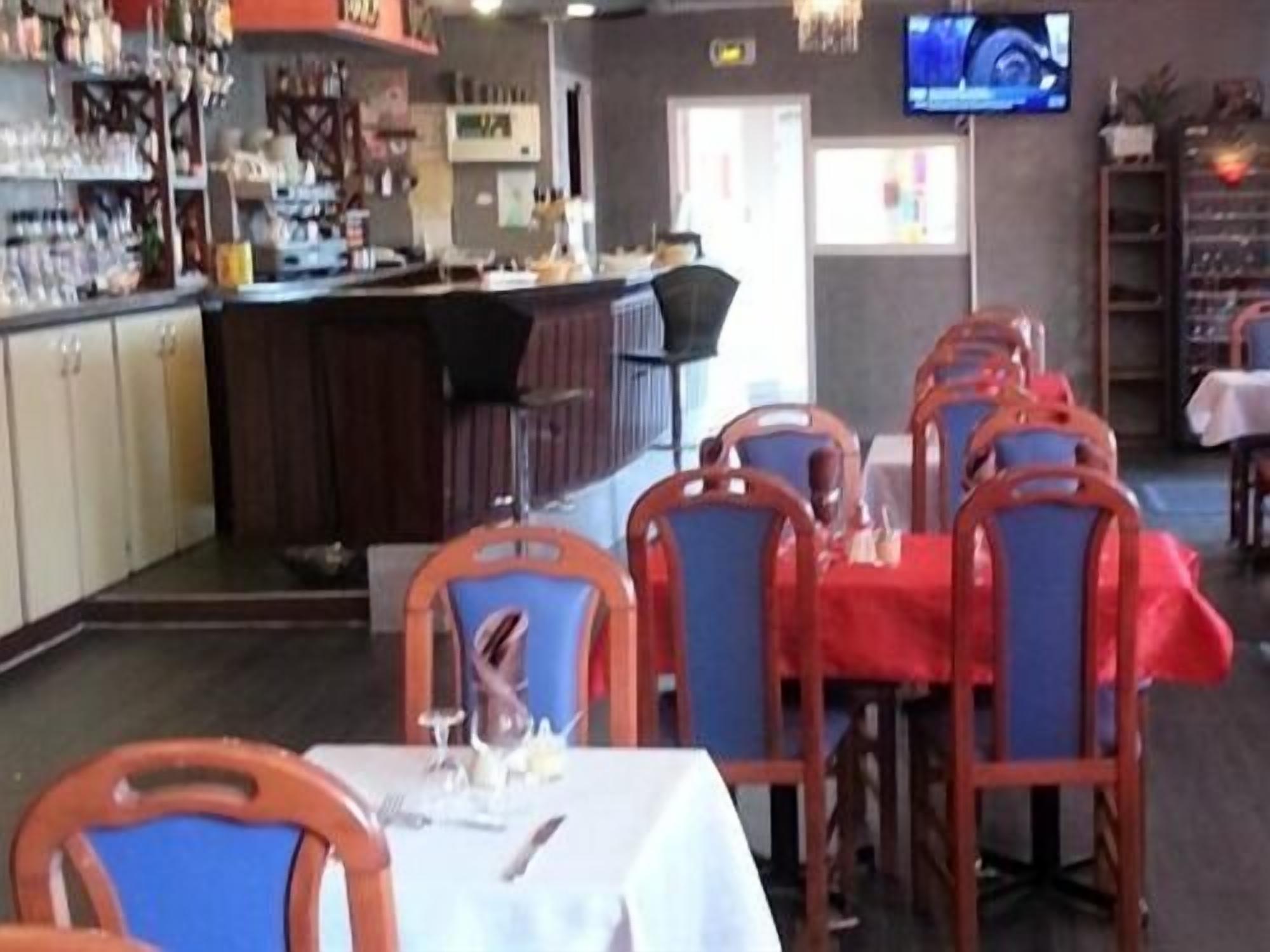 Ein Restaurant mit gedeckten Tischen, einer Bar und einem Fernseher an der Wand.