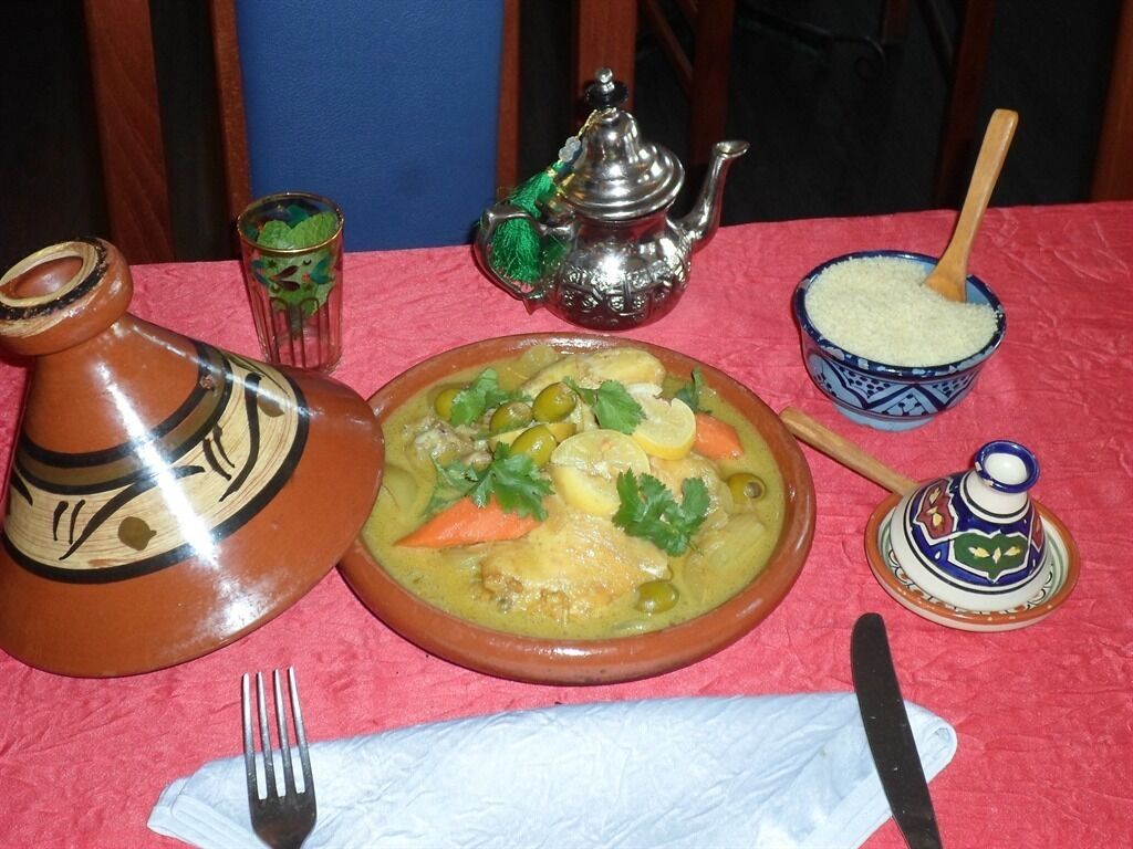 A table with a clay pot, a teapot, a bowl of rice, and a plate of food.