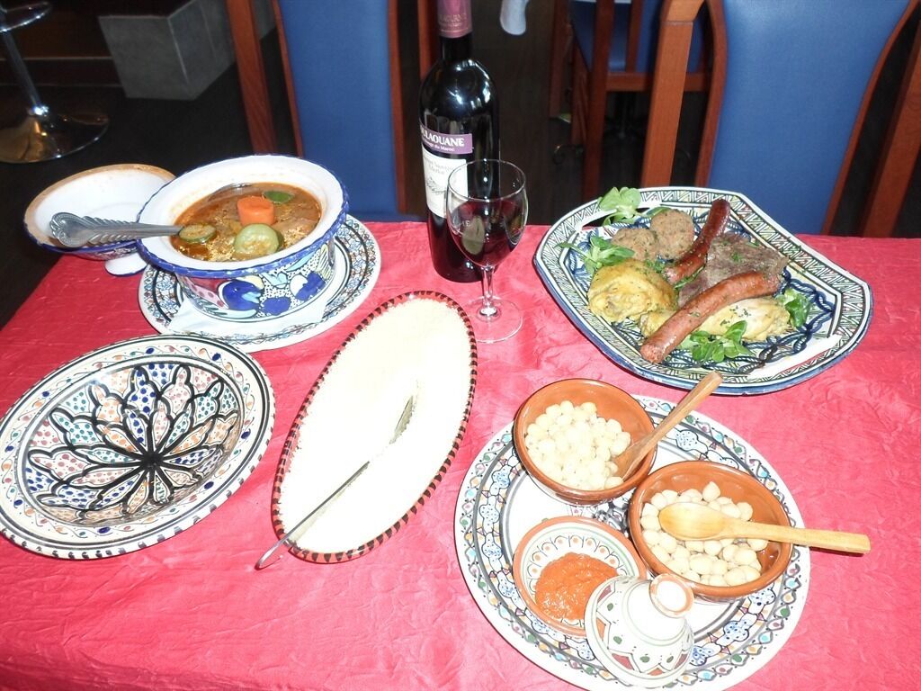 Una mesa servida con diversos platos, una botella de vino y un cuenco decorativo.