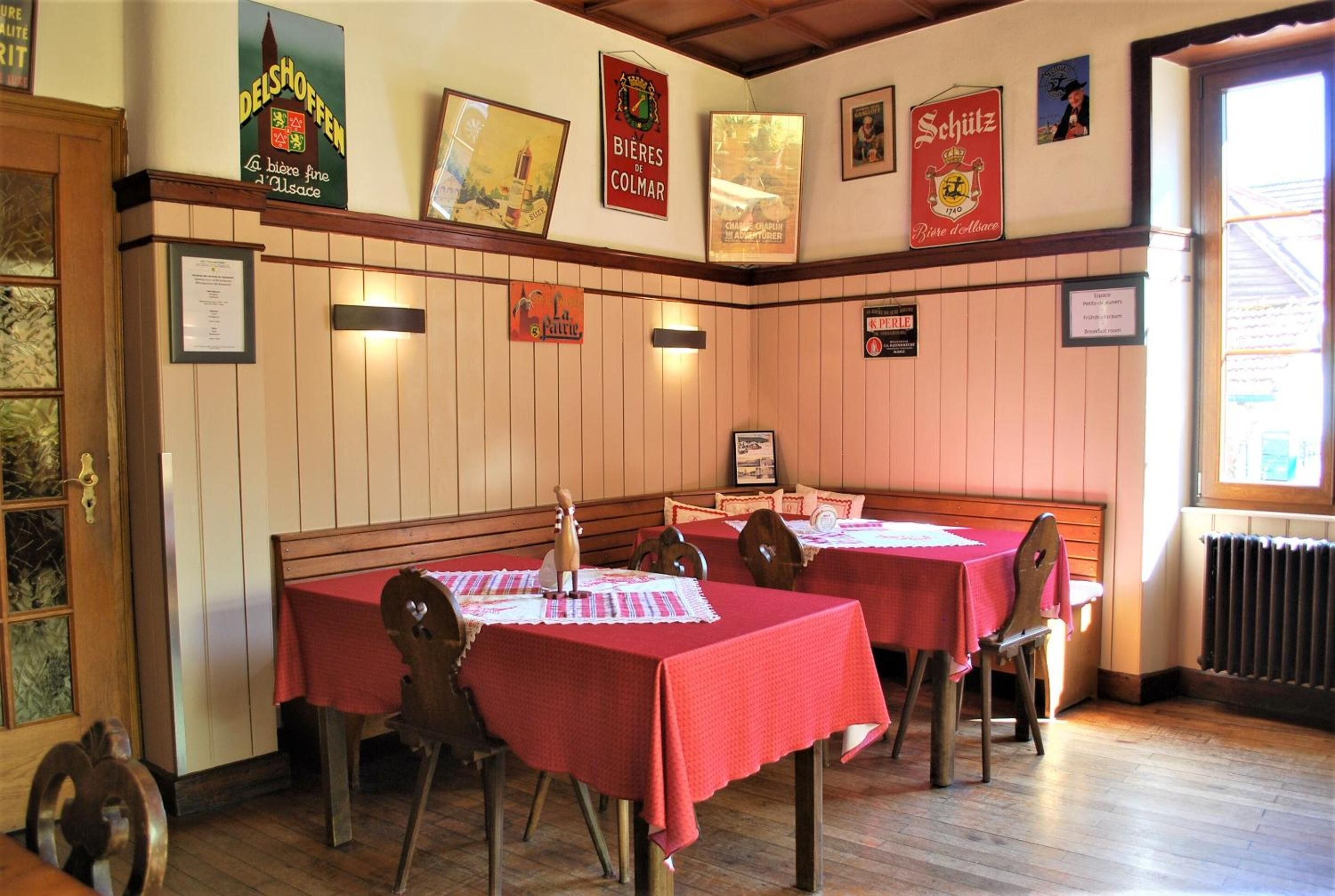 Un restaurante con paneles de madera, manteles rojos y cuadros en las paredes.