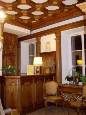 Une pièce avec des lambris en bois, un banc en bois et une fenêtre ornée de plantes.