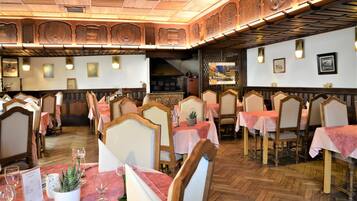 Un restaurant avec des meubles en bois, des nappes roses et un parquet à motifs en chevrons.