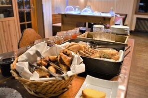 A breakfast buffet with bread, pastries, and beverages.