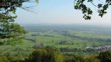 Ein weiter Panoramablick auf ein grünes Tal mit verstreuten Gebäuden, aufgenommen von einem hohen Aussichtspunkt.