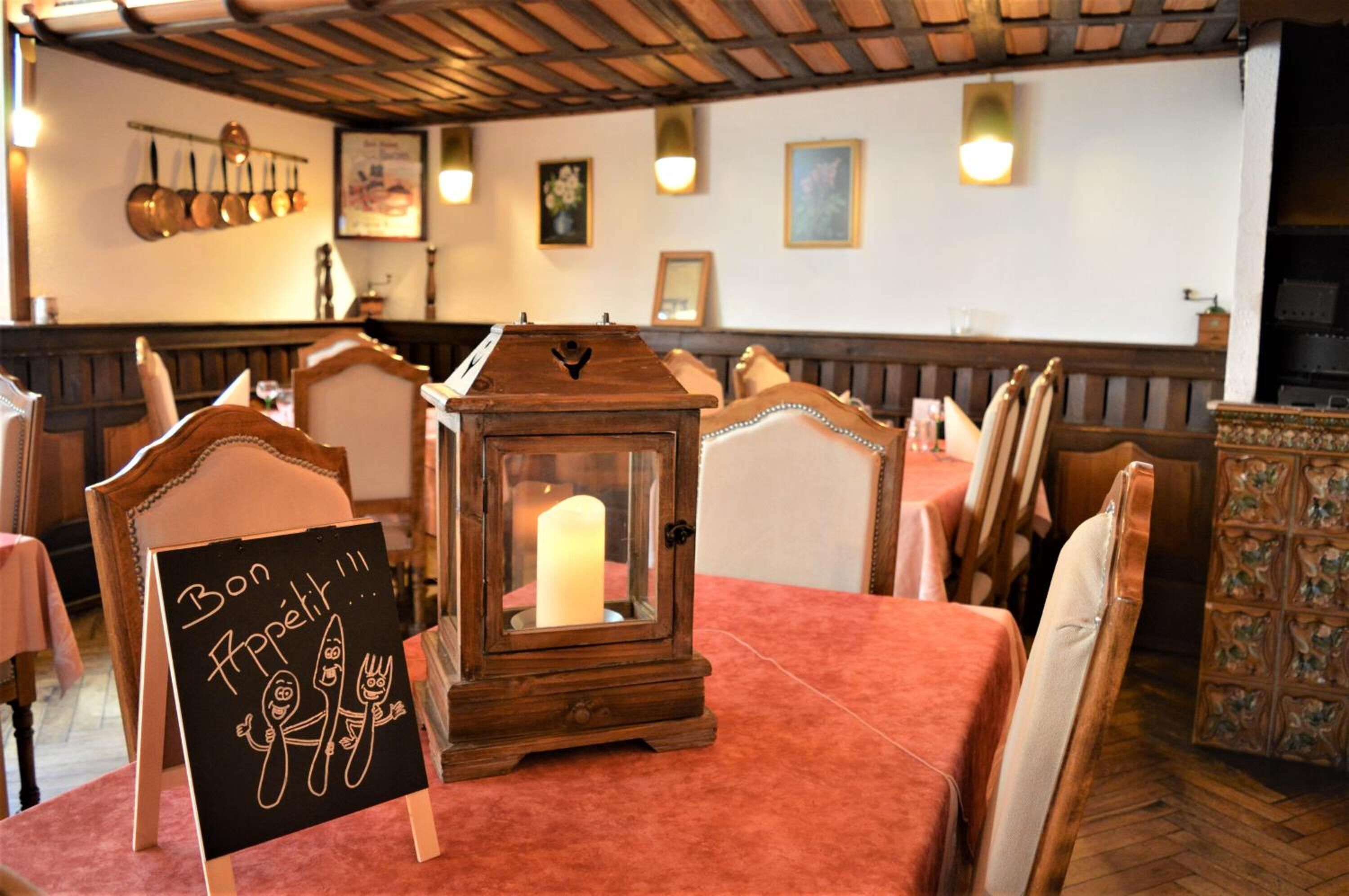 A restaurant interior with wooden furniture, a candle in a lantern, and a sign reading "Bon Appetit."