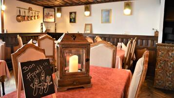 A restaurant interior with wooden furniture, a candle in a lantern, and a sign reading "Bon Appetit."