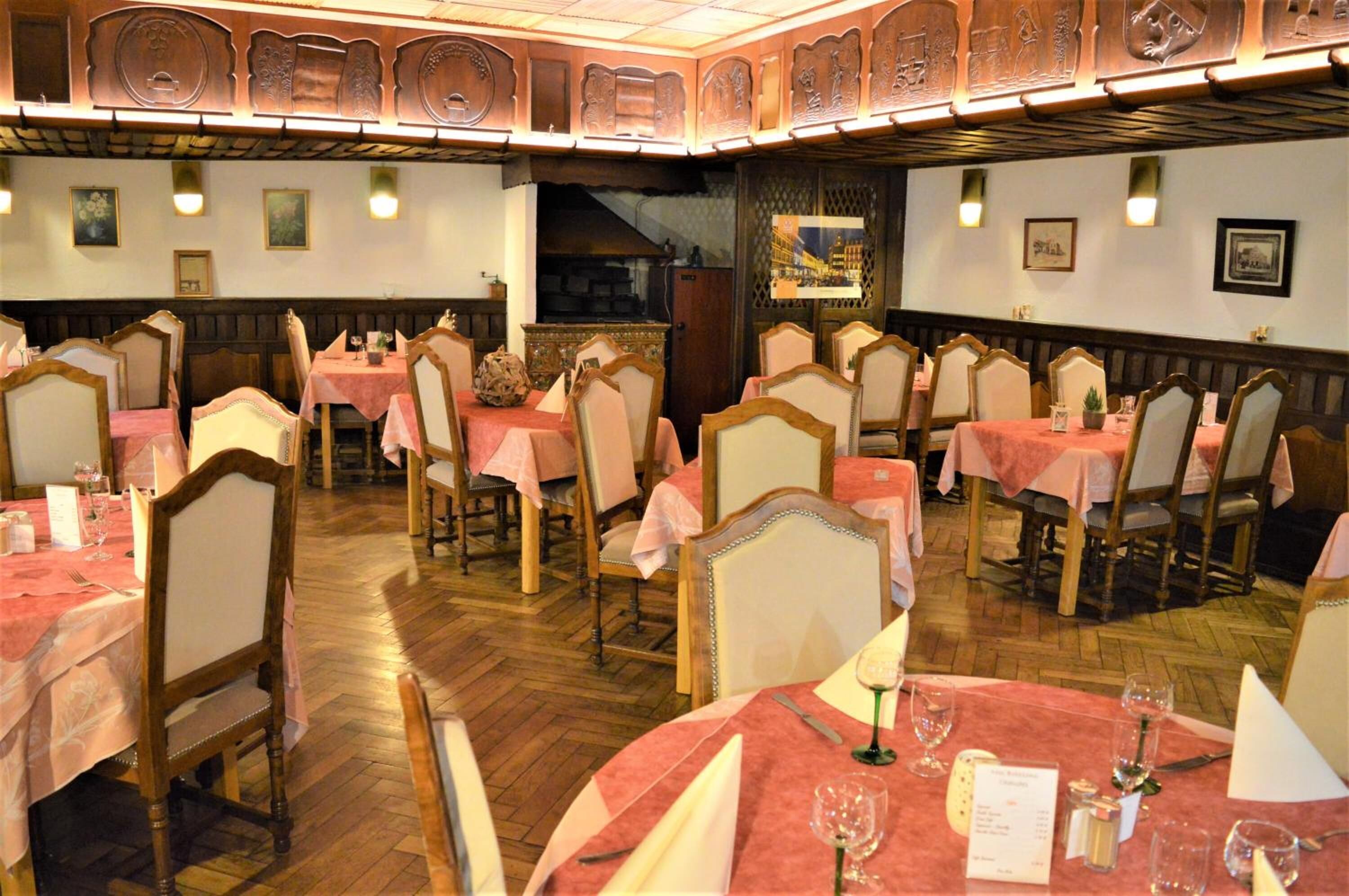 A restaurant with multiple tables and chairs, wooden paneling on the walls, and framed pictures on the walls.