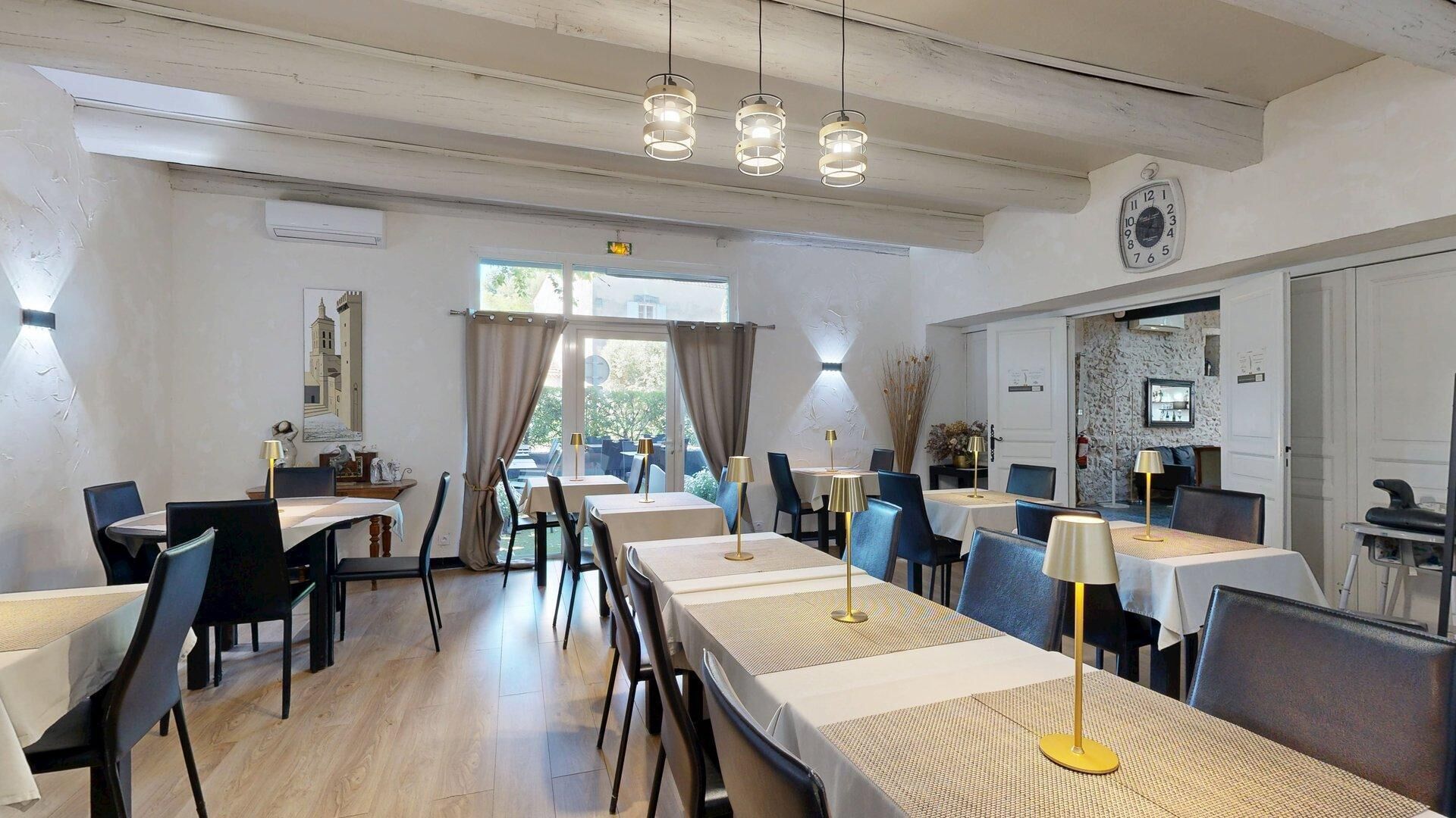A dining area with tables, chairs, pendant lights, and a view of the outdoors.