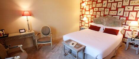 A neatly arranged bedroom with a large bed, two bedside tables with lamps, a chair, and a desk.