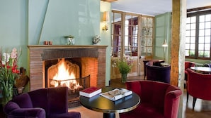 A cozy room with a fireplace, comfortable seating, and a view of the dining area.