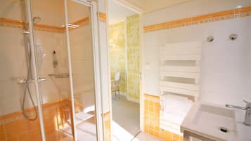 Un baño con cabina de ducha de vidrio, lavamanos e inodoro.