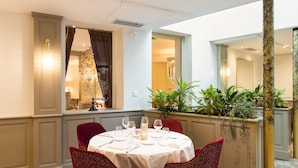A dining area with a round table set for four, red upholstered chairs, and a white tablecloth.
