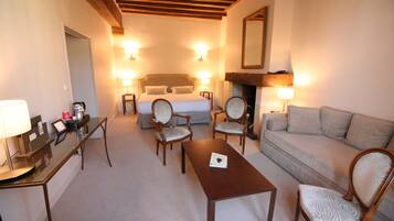 Una habitación de hotel con cama, dos sillones, un sofá, una mesa y un escritorio con lámpara.