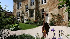 A stone building with multiple windows and a paved driveway.