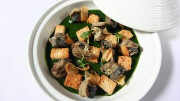 Un tazón de sopa de mariscos con tostadas y vegetales verdes.