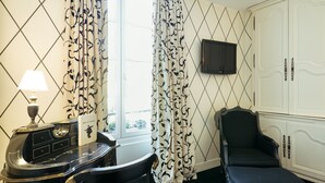 A hotel room with a desk, chair, and a television mounted on the wall.