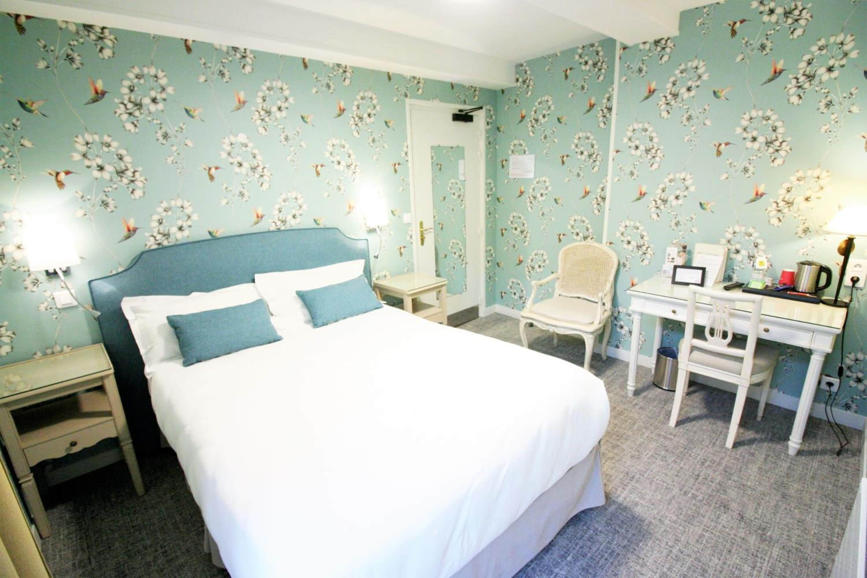 A bedroom with a bed, a desk, a chair, and a nightstand.