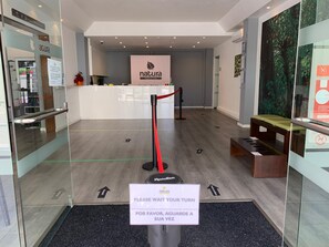 Ein Empfangsbereich mit einem Schild, auf dem steht: 'Bitte warten Sie' und 'Por favor, aguarde a su vez'.
