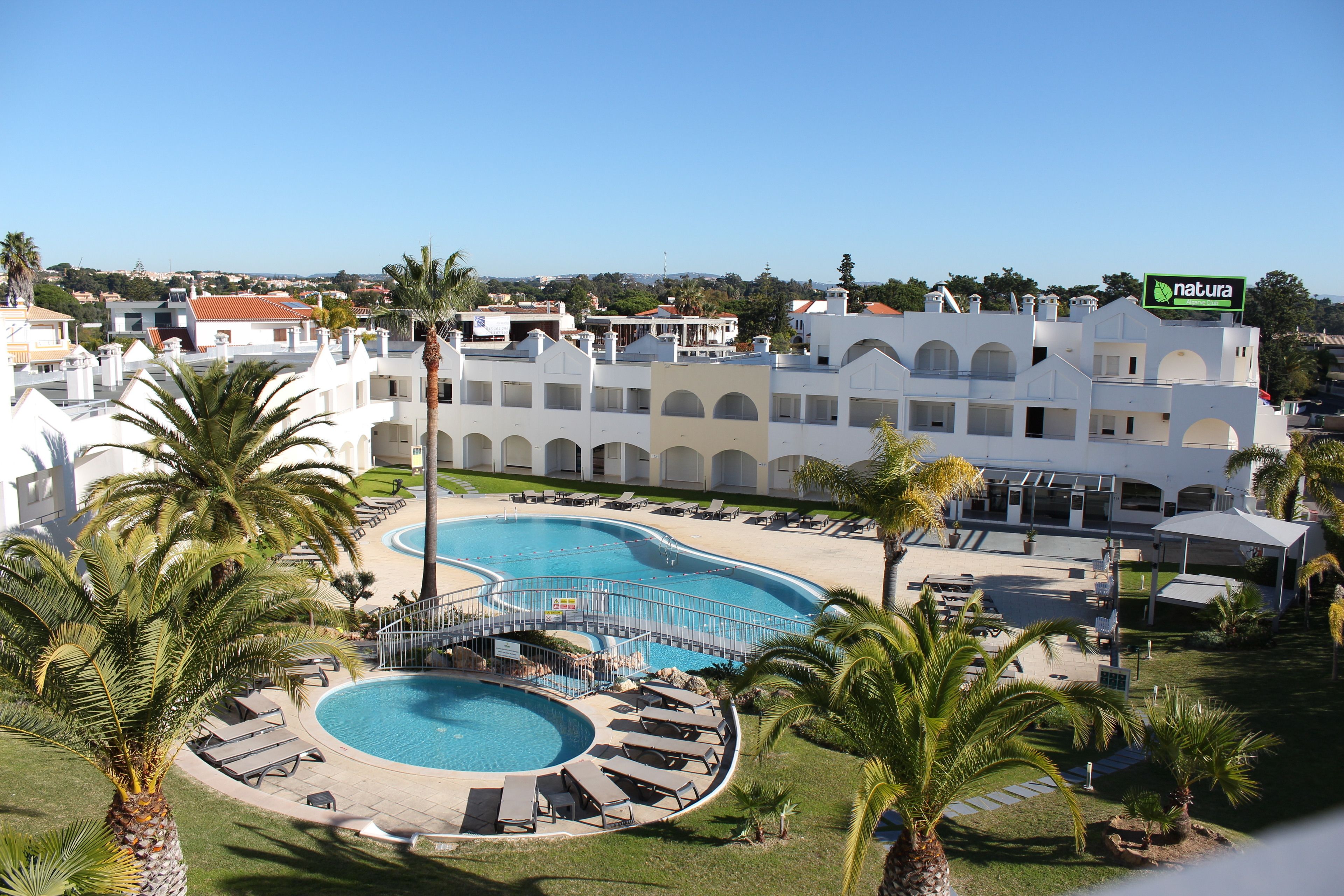 Ein Resort mit einem großen Schwimmbecken, Palmen und Blick auf die Umgebung.
