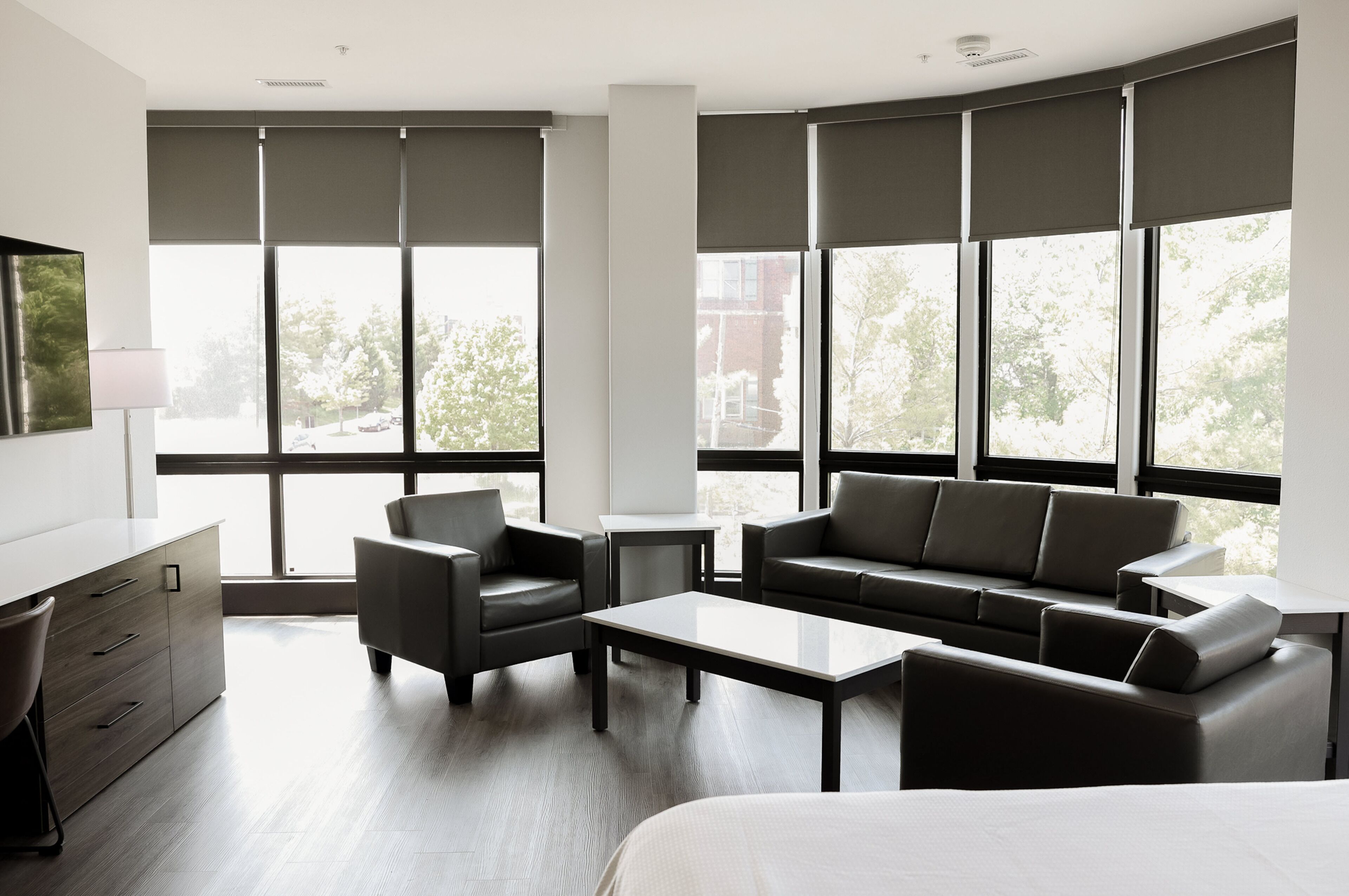 A modern hotel room with a large bed, a sofa, a desk, and a chair.