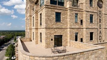 A stone building with a rooftop patio, multiple windows, and a view of the surrounding area.