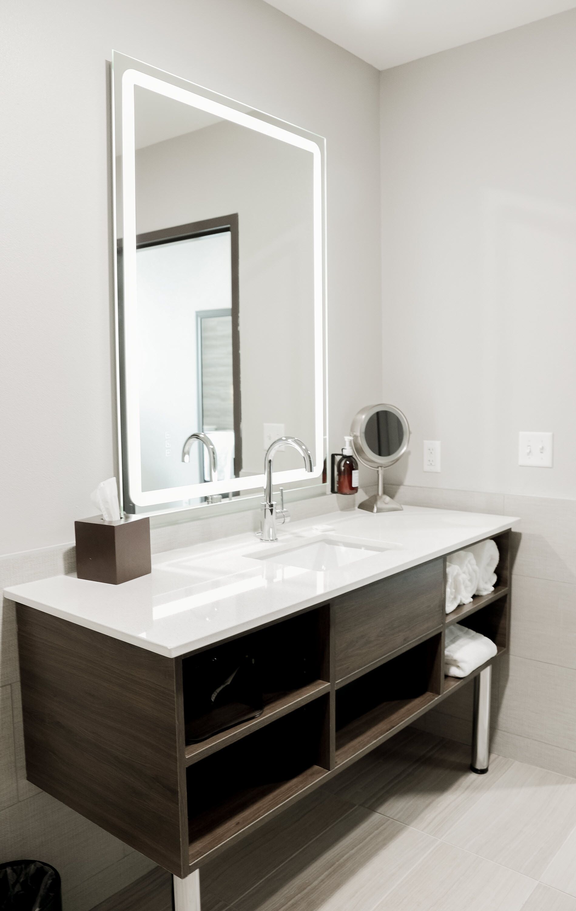 Un baño moderno con un espejo grande, un lavabo y un mueble de tocador con estantes.