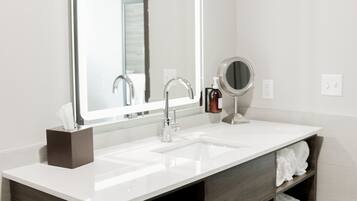 Un baño moderno con un espejo grande, un lavabo y un mueble de tocador con estantes.