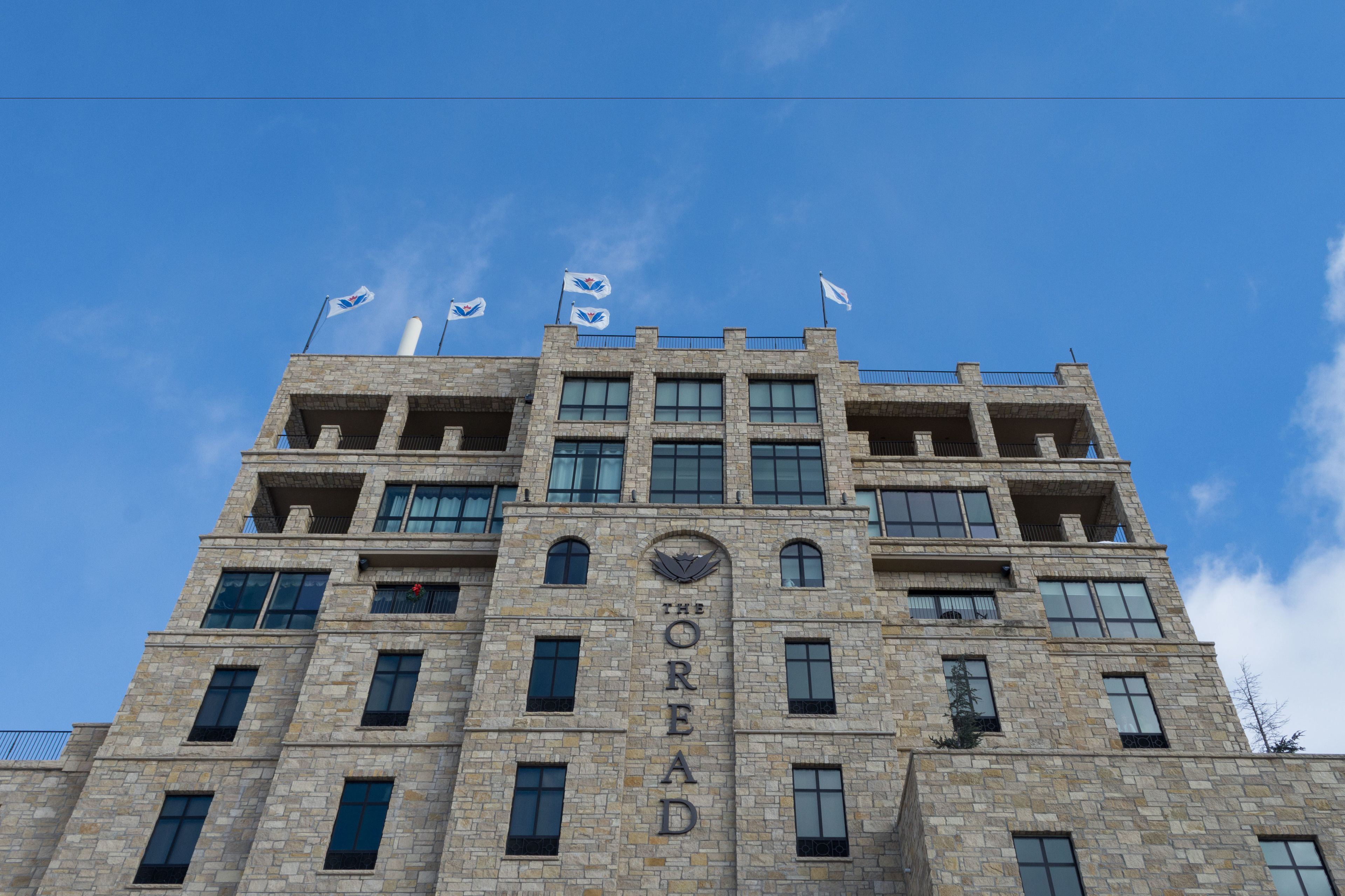 Um edifício de vários andares com fachada de pedra, várias varandas e céu claro.