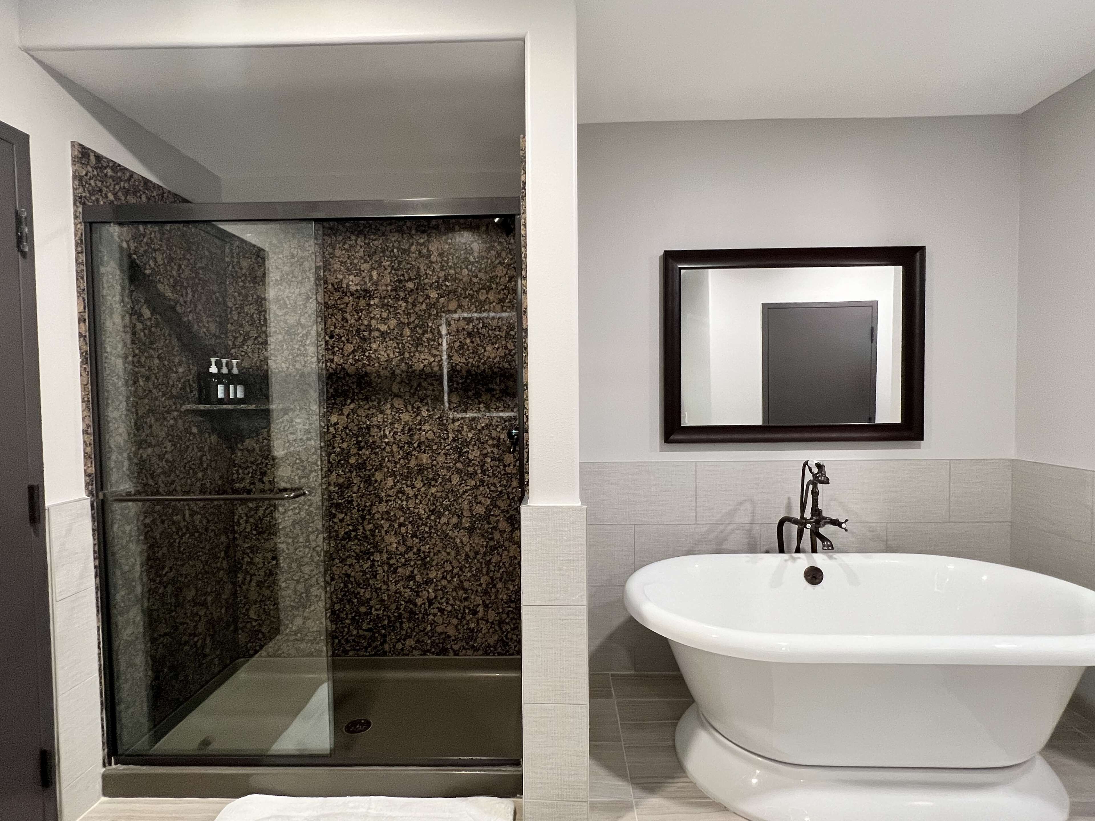 Ein Badezimmer mit einer gläsernen Duschkabine und einer freistehenden Badewanne.