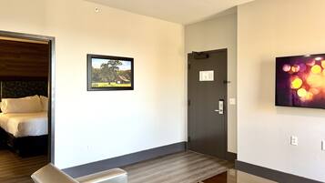 A hotel room with a bed, a sofa, a TV, and a door.