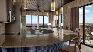Una cocina con una isla grande, paredes de piedra y vistas al paisaje.