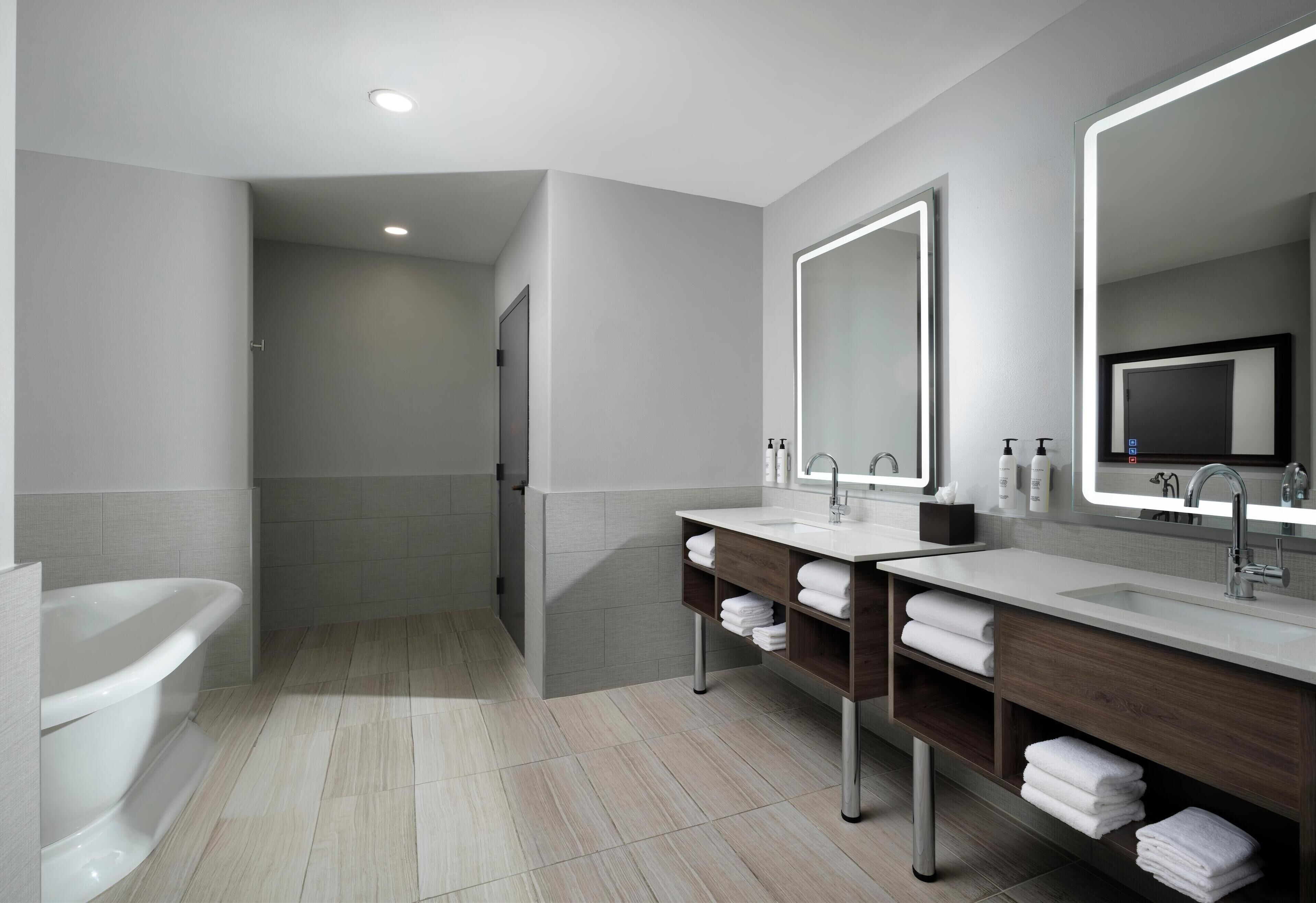 Une salle de bain moderne avec deux lavabos, un grand miroir et une baignoire.