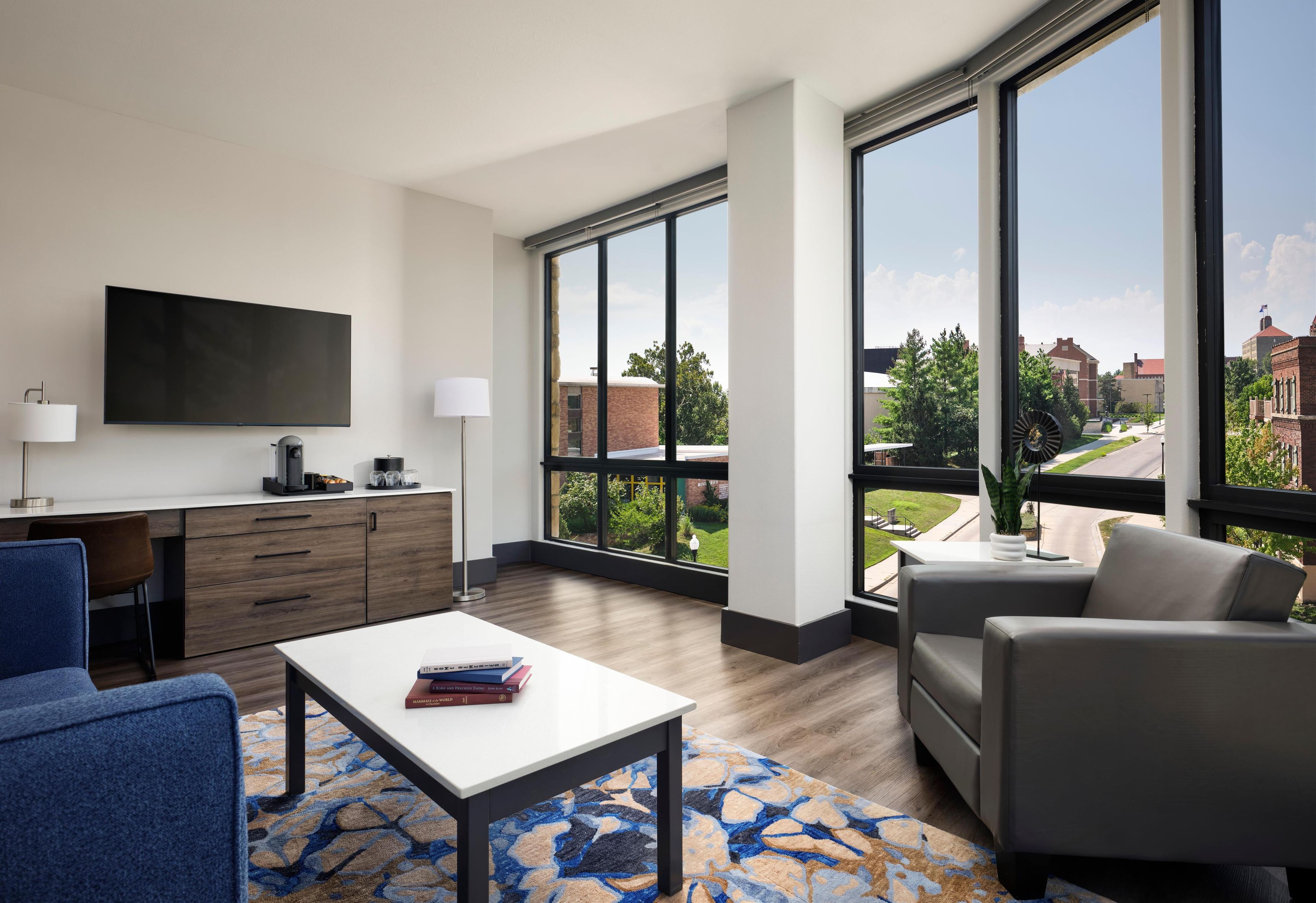 A modern living room with a flat-screen TV, a coffee machine, and a dining table.