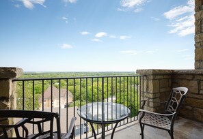 A balcony with a glass table and two chairs, overlooking a green landscape and buildings. - The Oread Lawrence, Tapestry Collection by Hilton (Lawrence)