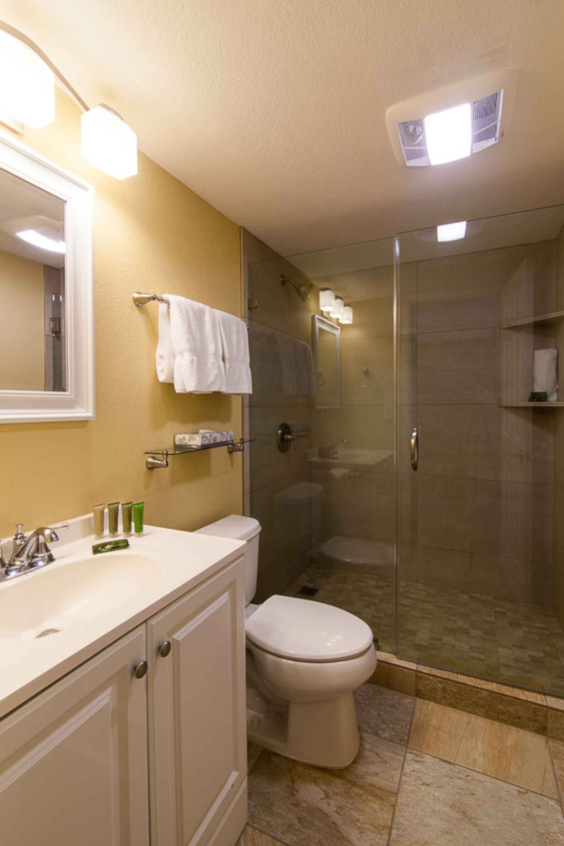 Een badkamer met douche, toilet en wastafel.