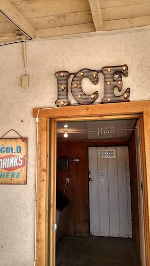 A wooden door with a sign above it that reads 'ICE' and another sign to the left that says 'COLD DRINKS HERE'. - The Atomic Blue Motor-Inn (Monticello)