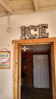 Uma porta de madeira com uma placa acima que diz 'ICE' e outra placa à esquerda que diz 'BEBIDAS FRIAS AQUI'.