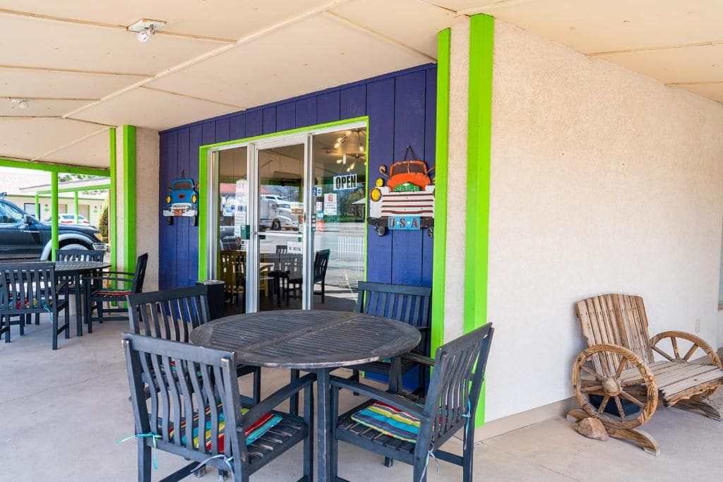 Un espace patio extérieur avec une table ronde et des chaises, un mur bleu et vert, et une petite décoration représentant le drapeau américain.