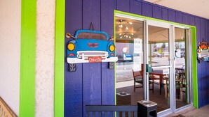 Une devanture de magasin aux couleurs bleu et vert, un décor en forme de voiture suspendu, et une porte vitrée sur laquelle est inscrit : « GLACES ET BOISSONS GAZÉIFIÉES ».