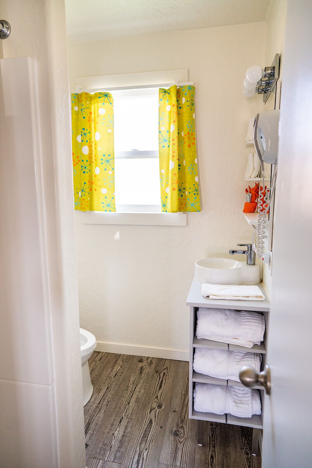 Een badkamer met een toilet, wastafel en een plank met handdoeken.