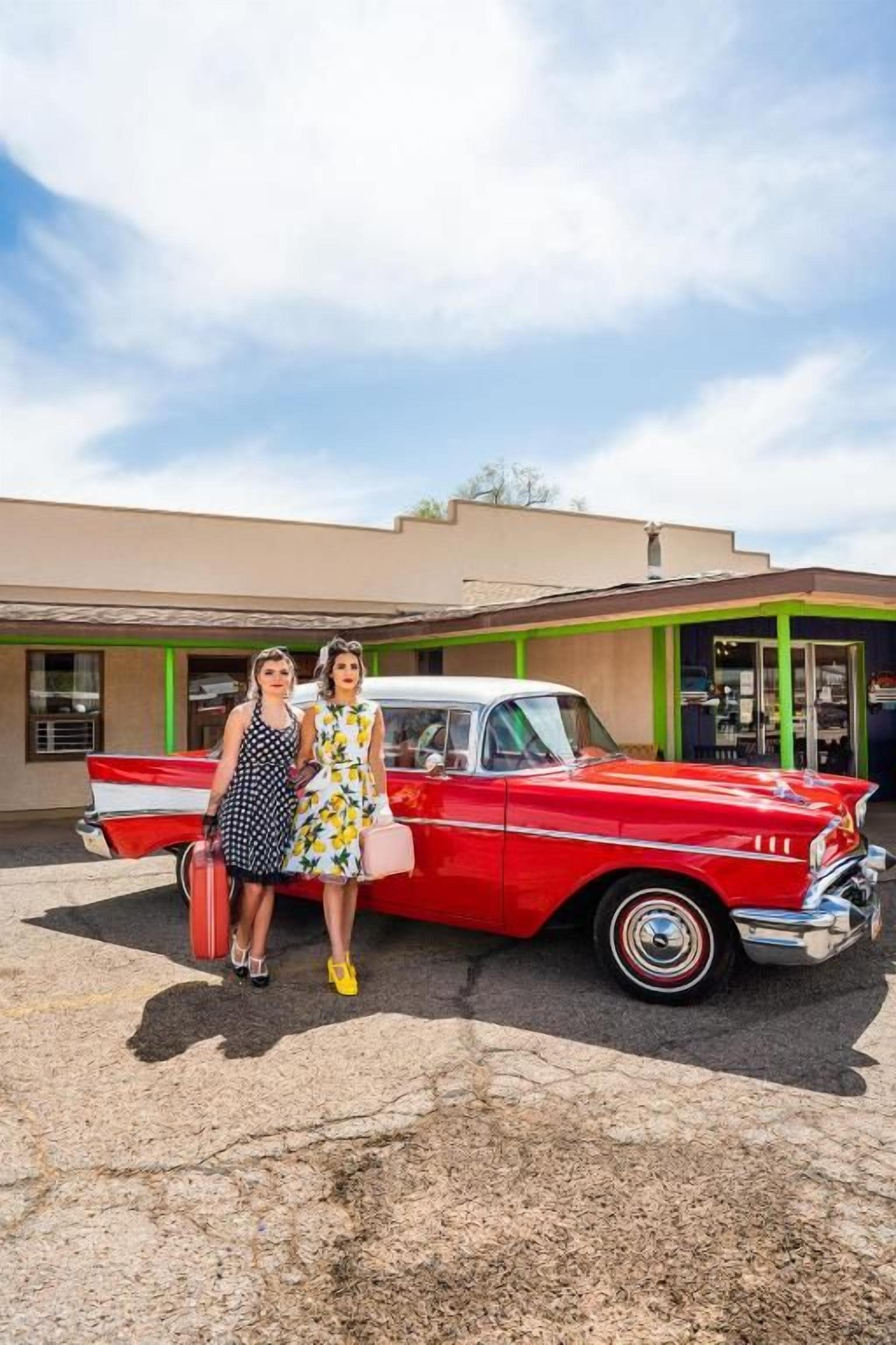 Une voiture rouge ancienne est garée devant un immeuble à la façade verte.