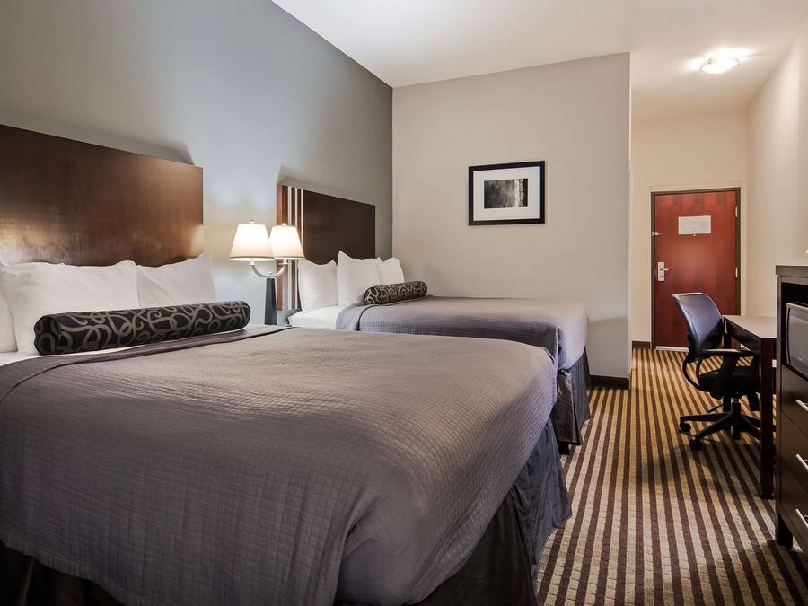 A hotel room with two beds, a desk with a computer, a TV, and a microwave.