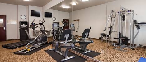 Un centre de remise en forme équipé de tapis de course, de vélos elliptiques et d'appareils de musculation.